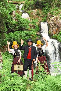 Das  Trachtentrio lädt zum Schinkenfest beim Wasserfall ein.  Foto: Stadtverwaltung Foto: Schwarzwälder-Bote