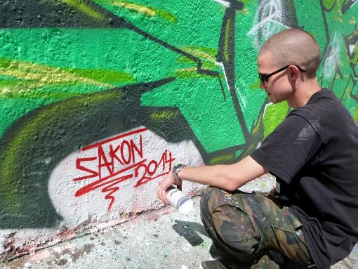 Sakon blickt auf sein fertiges Graffito mit Schriftzug. Foto: Maier