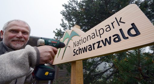 Nationalpark-Direktor Wolfgang Schlund montiert bei Seebach ein Holzschild mit der Aufschrift Nationalpark Schwarzwald.  Foto: dpa