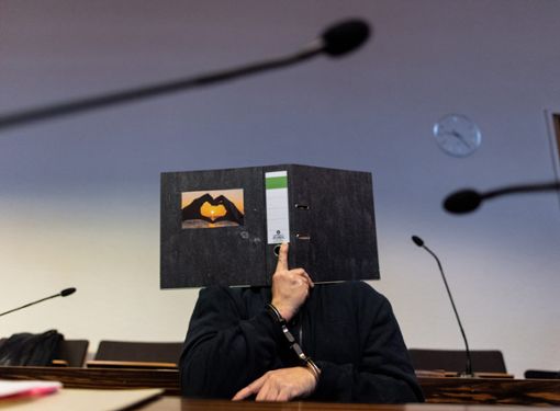 Freiburg: Der 58-jährige Angeklagte sitzt im Gerichtssaal im Landgericht und hält einen Aktenordner mit einem Herz aus zwei Händen vor sein Gesicht. Ihm werden die Entziehung Minderjähriger und schwerer sexueller Missbrauch von Kindern vorgeworfen. Der Mann aus Blomberg in Nordrhein-Westfalen soll im Mai 2013 mit der damals 13-Jährigen Maria ins Ausland geflüchtet sein, ohne dass deren Eltern davon wussten. Foto: dpa