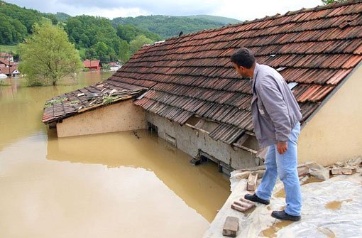 Ein Mann blickt vom Dach seines Hauses auf die überflutete Straße in Pozega, 200 Kilometer süd-westlich von Belgrad. Foto: dpa