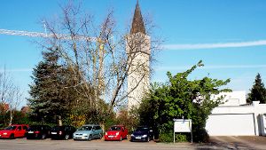 Wo jetzt noch Autos stehen, soll bald der Zugang zur neuen Frommerner Kirche mit Grüninseln angelegt werden. Dann soll auch die Sicht auf den Turm besser sein. Foto: Hauser