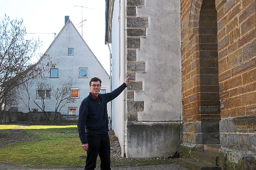 Auch Pfarrer Johannes Zimmermann kann das Datum auf der Außenmauer der Kirche nicht genau entziffern. Foto: Fischer