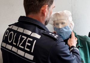 Der Pressesprecher des Heilbronner Polizeipräsidiums, Gerald Olma, zeigt die Anwendung einer Spuckschutzhaube an einer Puppe. Foto: dpa