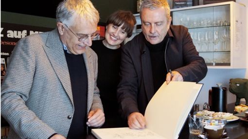 Kunststaatssekretär Arne Braun (von links) schaut mit Viktoria Tiedeke und Töni Schifer vom Vorstand an der historischen Theke ins Gästebuch des MPS-Studios in Villingen. Foto: Elena Baur