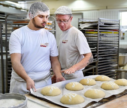 Muhammad Zamzam (links) und Schichtleiter Alex Rau werfen einen Blick auf  das Opa-Karl-Brot der Saurs mit dem geschwungenen K, das gerade frisch draufgestreut wurde. Foto: Hopp