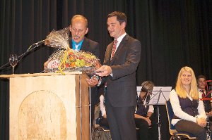 Der stellvertretende Rathauschef Jochen Borg (links) verpflichtete Bürgermeister Klaus Mack auf eine zweite Amtszeit und überreichte ihm zudem Vitamine für die kommenden Aufgaben. Foto: Krokauer