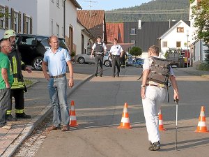 Hier, in der Schulstraße in Wilflingen, ist es passiert, hier sind die tödlichen Schüsse gefallen. Der Tatort im Hintergrund ist weiträumig abgesperrt, Bürgermeister Thomas Albrecht (Dritter von links) beobachtet die Szenerie.  Foto: Schulz
