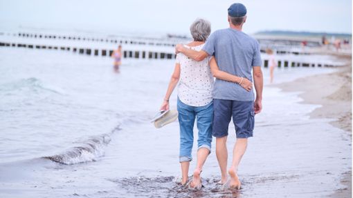 Frauen leben länger: Ein Rentnerehepaar geht an einem  Strand bei Rostock Arm in Arm spazieren Foto: dpa/Annette Riedl
