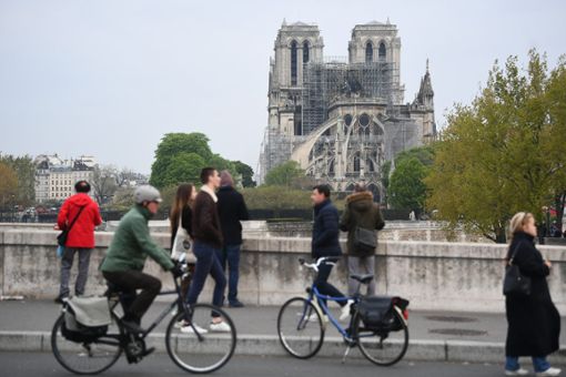 Fußgänger und Radfahrer betrachten die Kathedrale Notre-Dame am Tag nach dem Brand. Foto: Victoria Jones/PA Wire/dpa